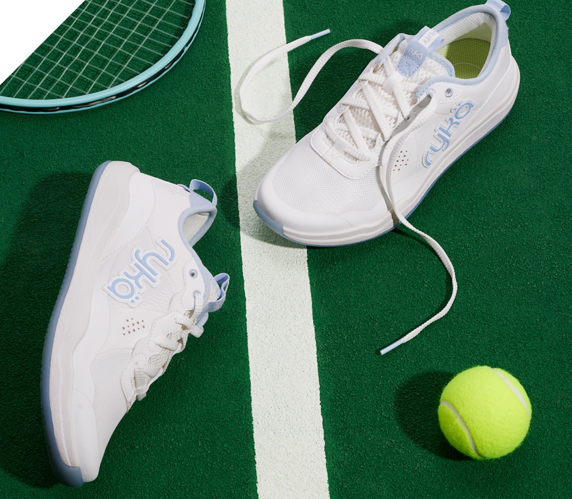a pair of Rykä court shoes on a tennis court alongside a tennis racket and a tennis ball