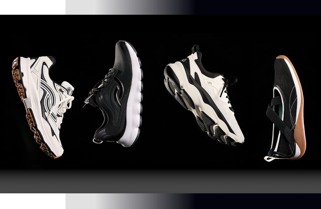 Four women's sneakers floating in the air. One is a black Mary Jane sneaker, two are white walking sneakers, and one is a black walking sneaker. 
