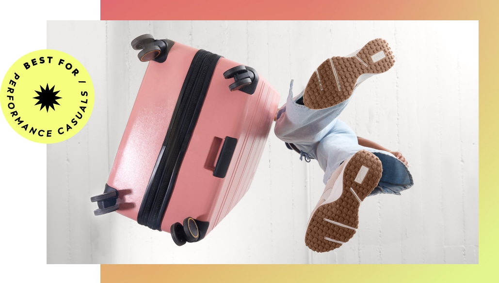 A woman pushing a pink suitcase, wearing cream and tan casual sneakers with brown gum soles. A yellow graphic says 