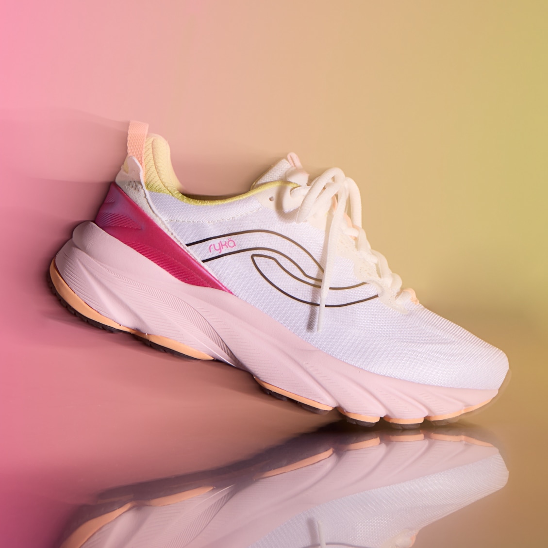 A white women's running sneaker with a pink sole displayed on a pink and yellow gradient background. 