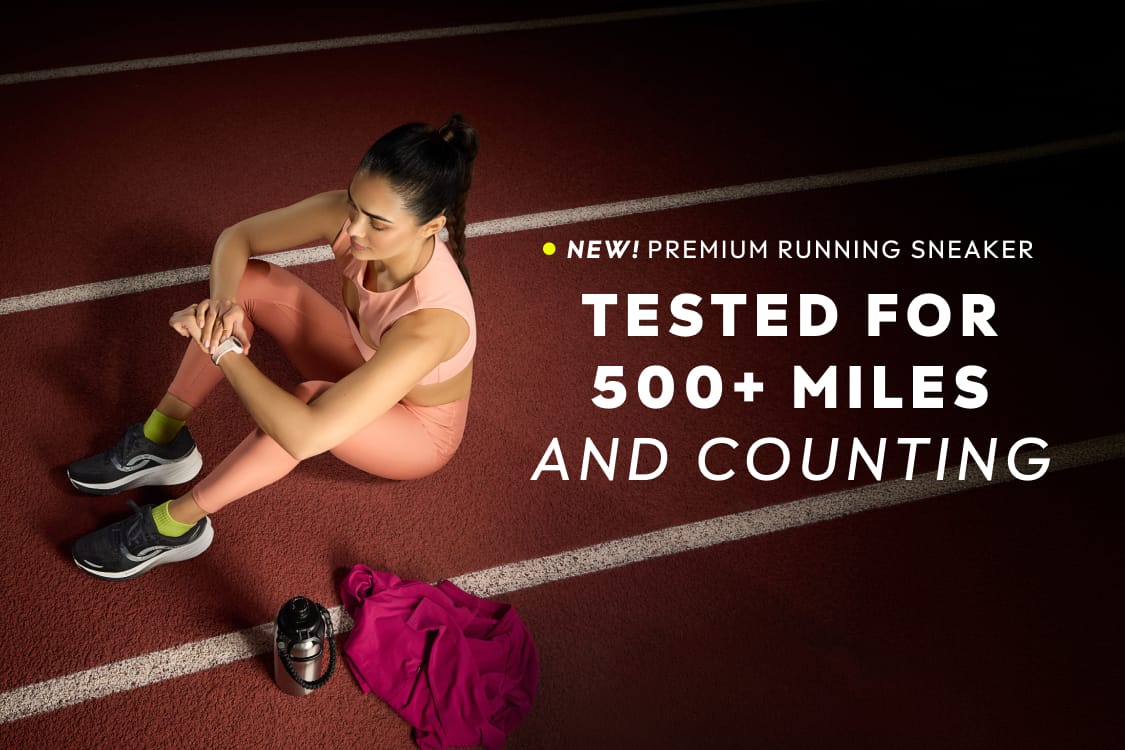 Woman sitting on a track wearing black and white running sneakers with bold text to the right reading “TESTED FOR 500+ MILES AND COUNTING.”