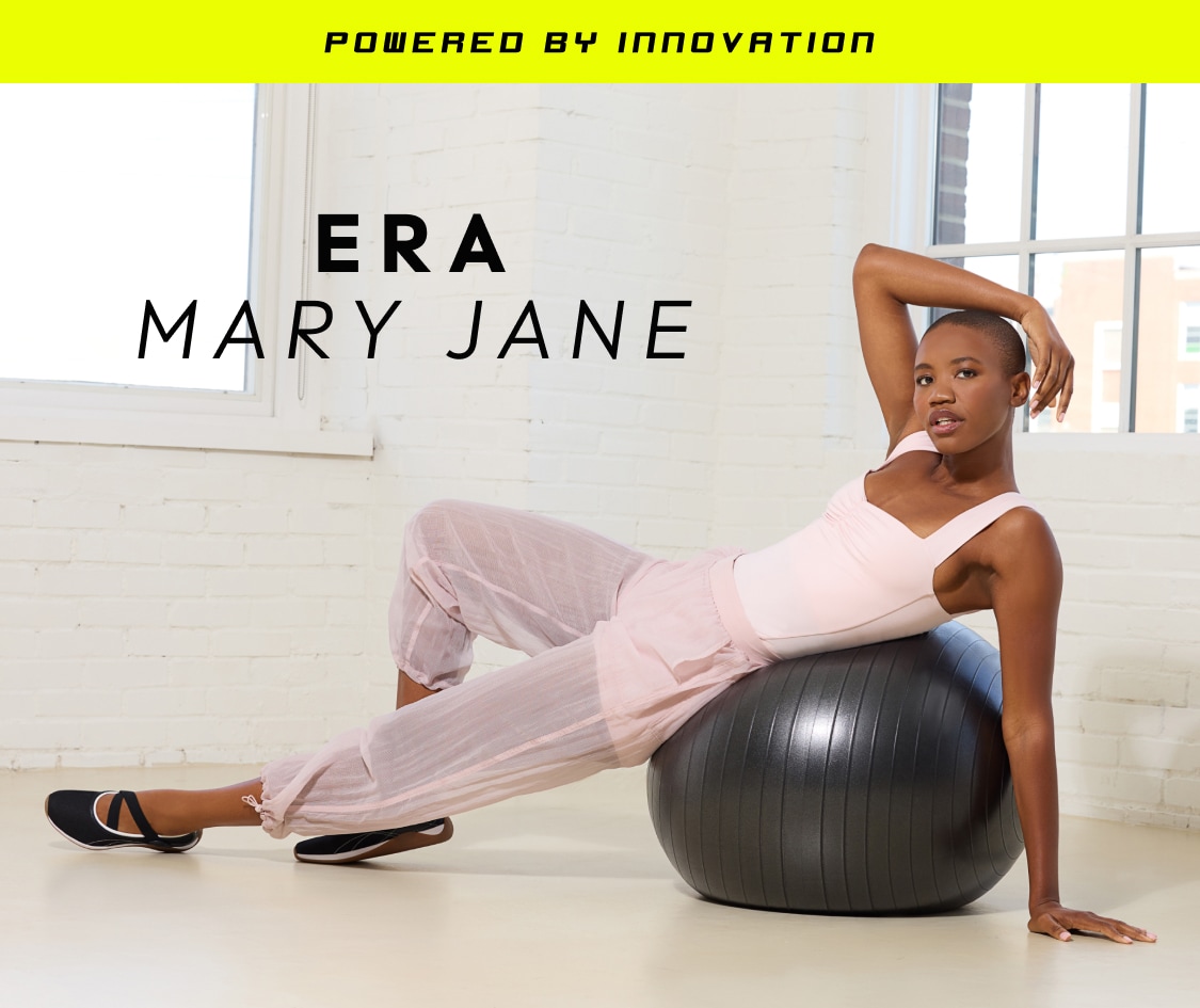 Woman in pink activewear posing on exercise ball, wearing black Mary Jane flats with white trim. Text above the model reads, 