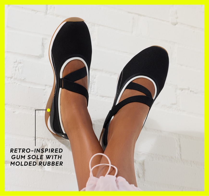 Closeup of a woman wearing a pair of black Mary Jane flats with white trim. Text to the left reads, 