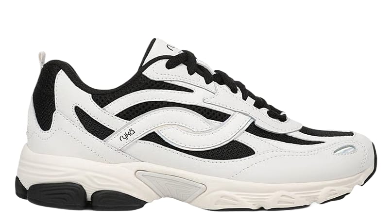 Side view of a women's white sneaker with suede panels, black accents, and a chunky sole. 