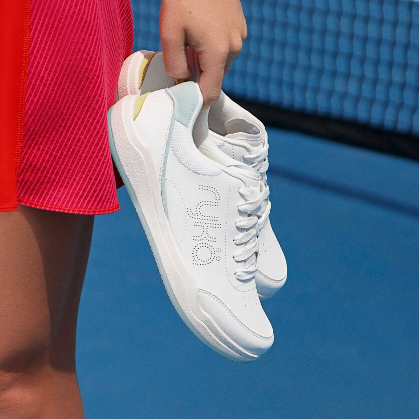 A model holding Rykä court shoes while on a tennis court