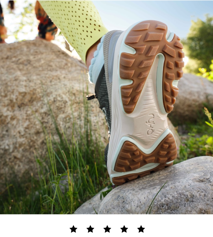 A model wearing Rykä Devotion X TR shoes while hiking on rocks