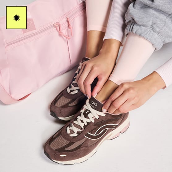 Woman adjusting the tongue of a pair of brown sneakers. 