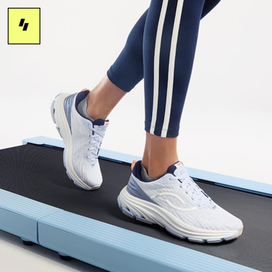 Woman on a walking pad wearing blue leggings and blue and white sneakers. 