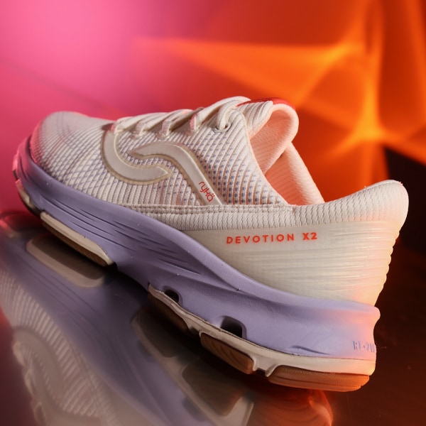 An angled view of the back of an off-white sneaker with a purple sole displayed on a pink and orange background. 