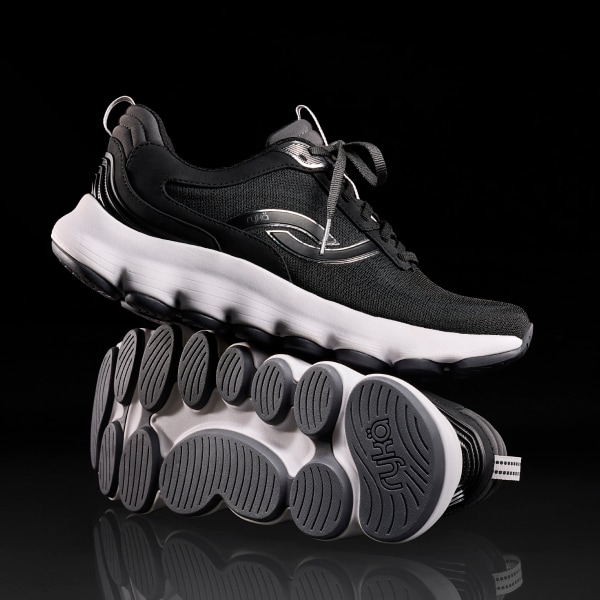 A pair of black walking sneakers with a white sole stacked on top of one another. One sole is facing forward, highlighting the Podflow technology. 