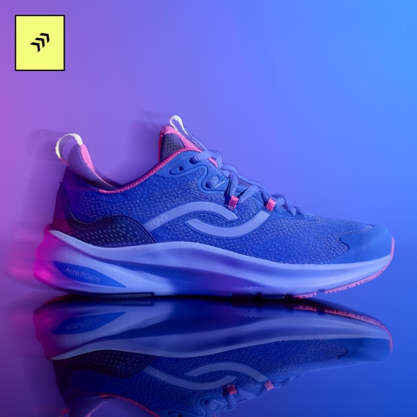 A side view of a blue women's training sneaker on a purple and blue gradient background. 