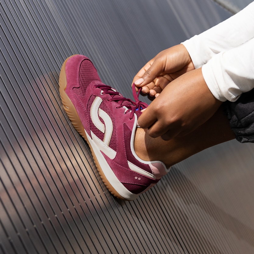 A model wearing a Rykä Candor shoe while tying the laces