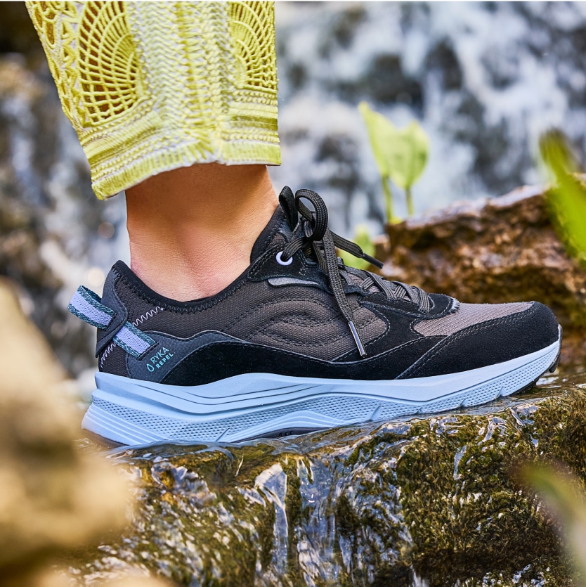 A model's foot wearing a Rykä Upside TR shoe while hiking on rocks